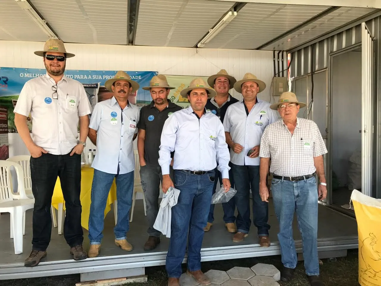 Equipe da cooperativa de chapéu, em pé no estande